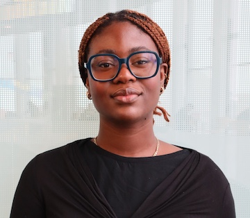 Mariam Onafowokan wears a black shirt and glasses and is smiling.